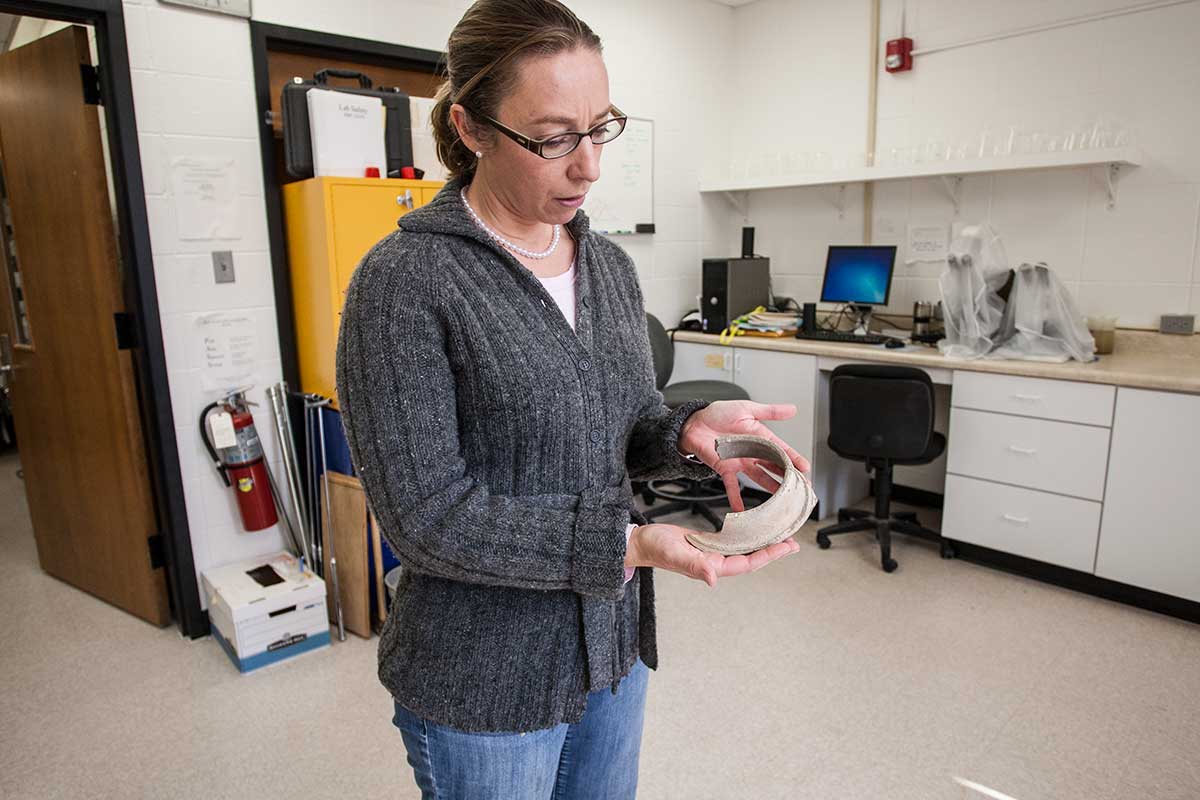 Professor Danielle Steen Fatkin holds a fragment of ancient pottery during an archaeology lab session. Students studied pottery that Fatkin collected in Dhiban, Jordan.