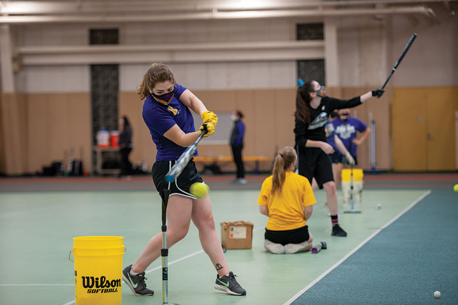 Senior Clare Hensley takes practices hitting off a tee during softball practice.