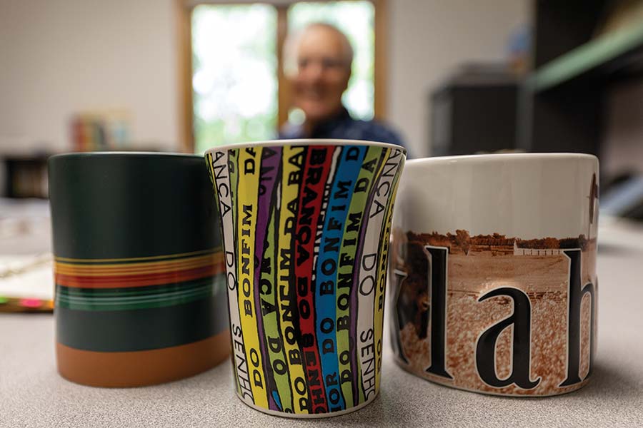 Julio sitting behind mugs he has displayed on his desk.