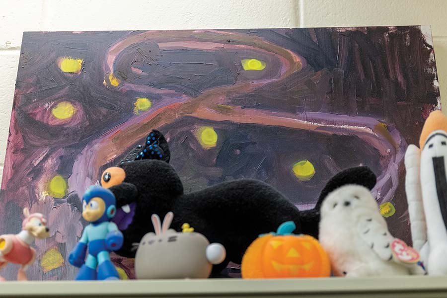 Painting and plushies sitting on a shelf.