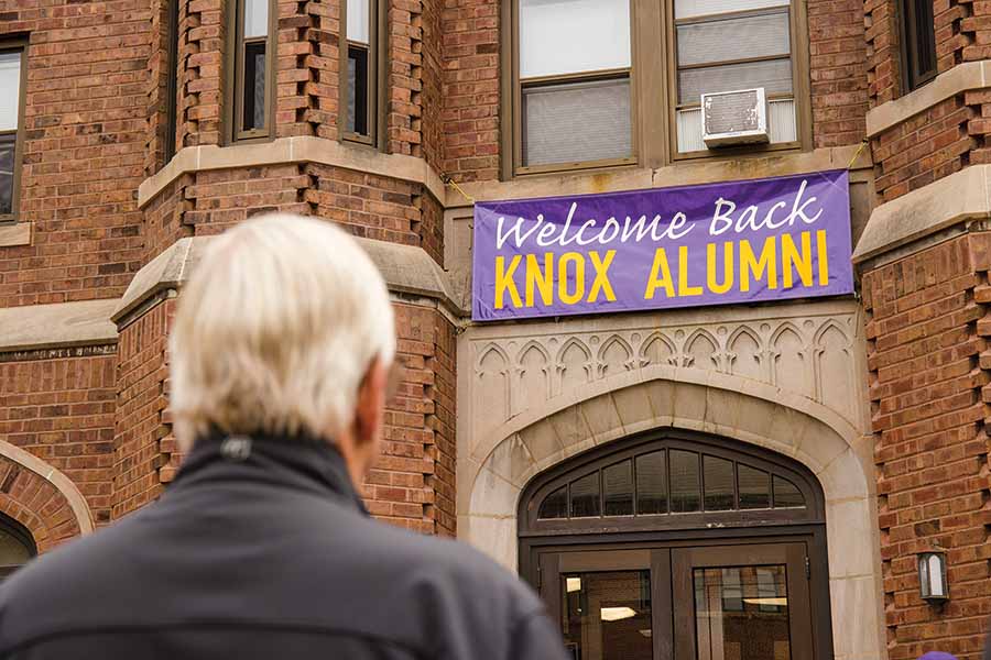 An alum looks towards Seymour Union at a sign that reads Welcome Back Knox Alumni.