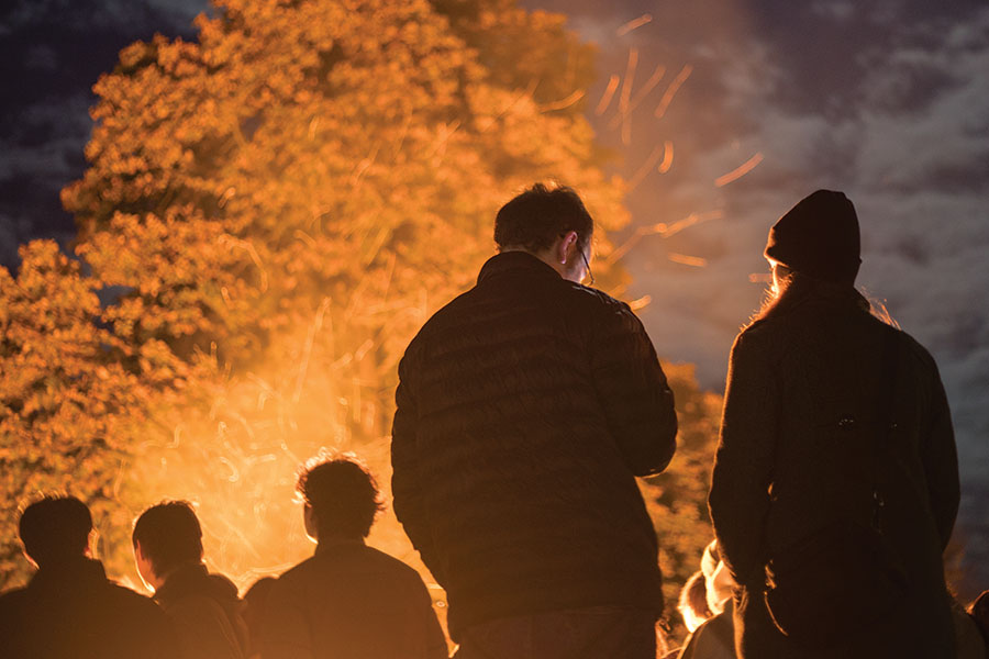 Students and alumni stand next to the Homecoming bond fire!