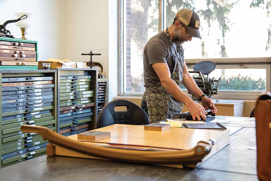 Nick Regiacorte standing at the letterpress making a print.