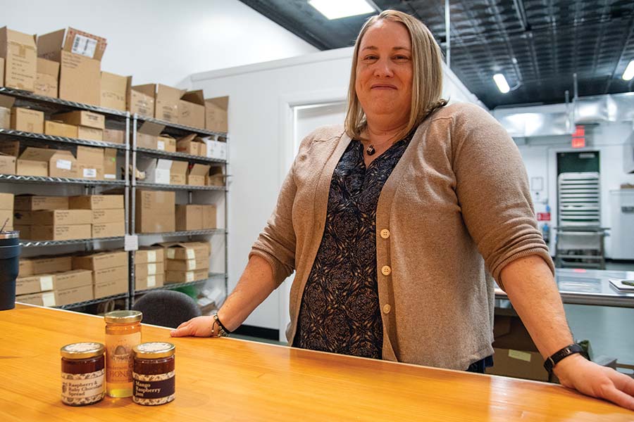 Nikki Malley standing behind a table with canned jams on it.