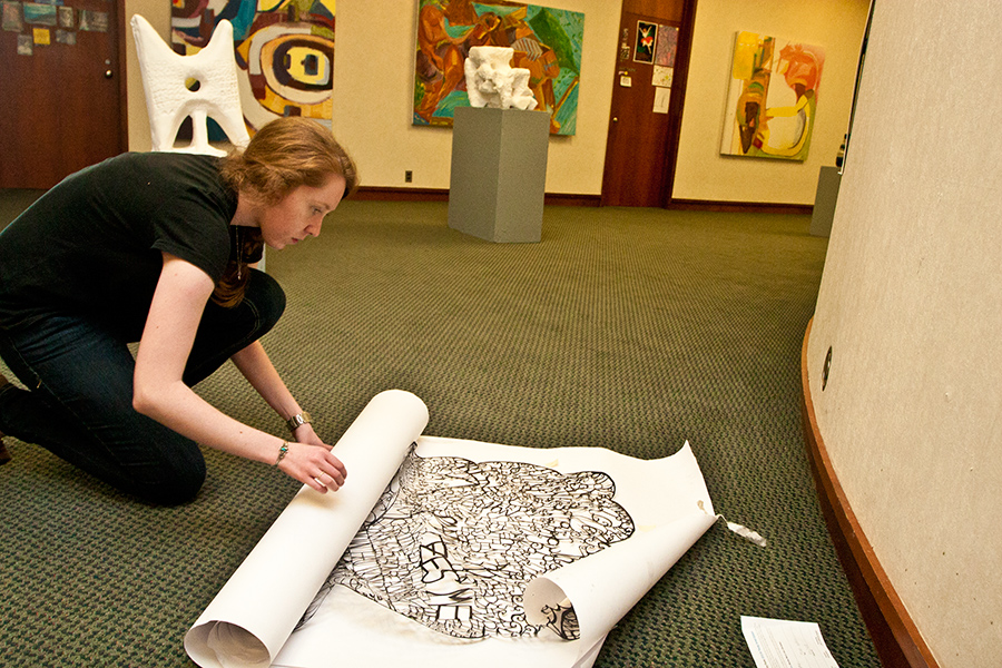 Katie O'Connor checks another student's fragile cut-paper art work that would be placed on the wall by the artist