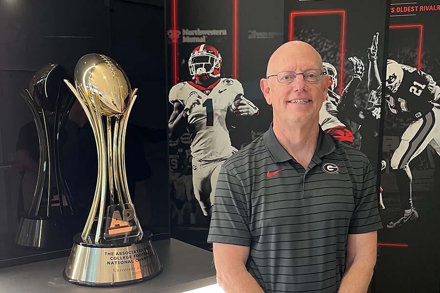 Large gold-colored football championship trophy sits to the left of Fred Reifsteck