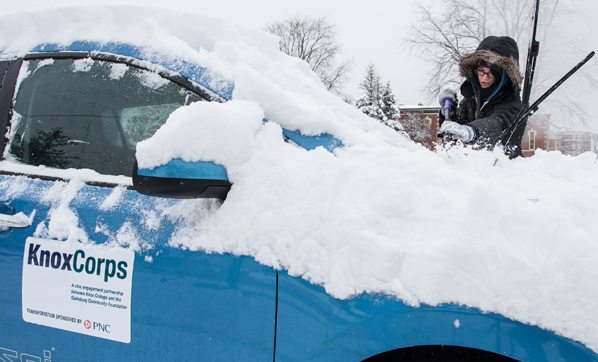 Student clears snow from electric car