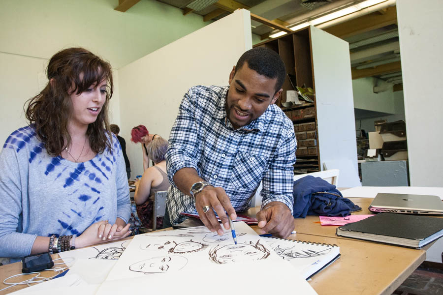 Student discusses her portfolio with her professor in painting class.