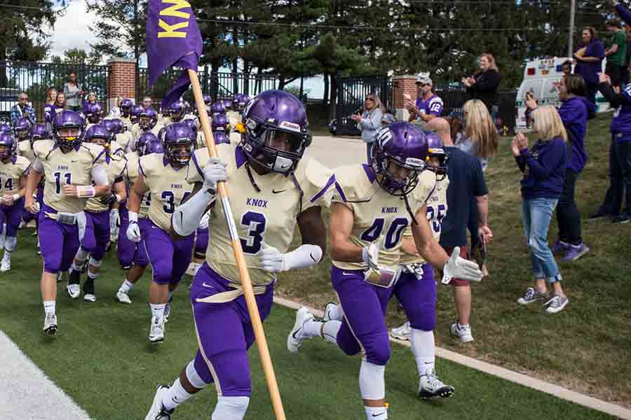 Armand Stricklin leading the Knox football team onto the field for a game against Carleton.