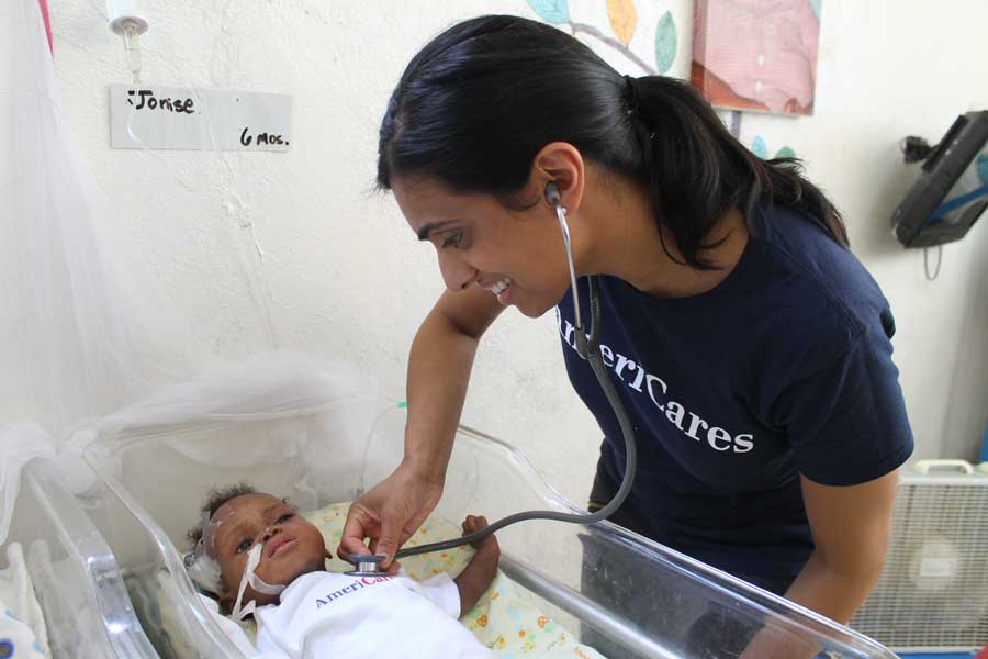 Dr. Varughese '00 with a child in a cholera treatment center in Haiti.