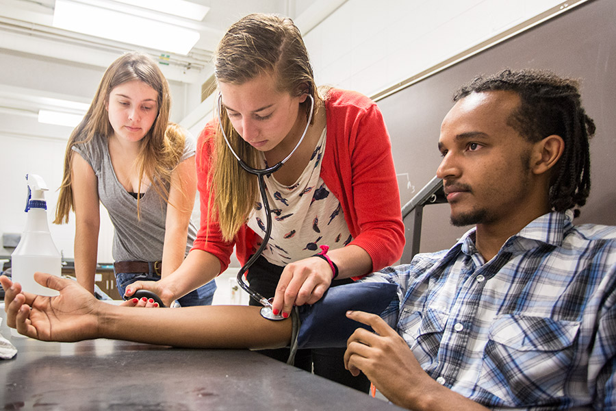 Knox students in a physiology lab practice checking blood pressure.