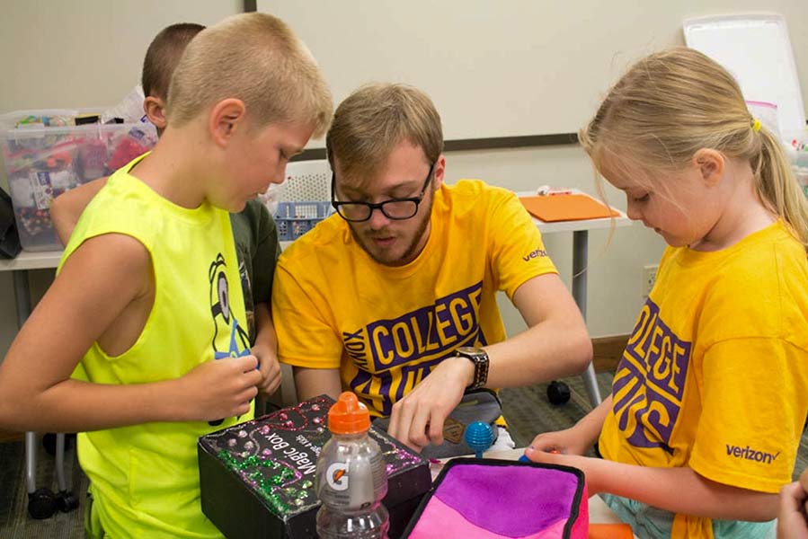 A Knox student assists kids during a class on magic.