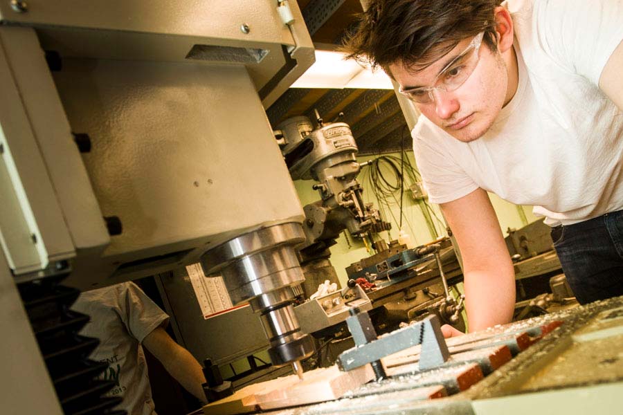 Will Parkinson of the Knox Engineers Club using a CNC mill to carve their club logo on a piece of wood.