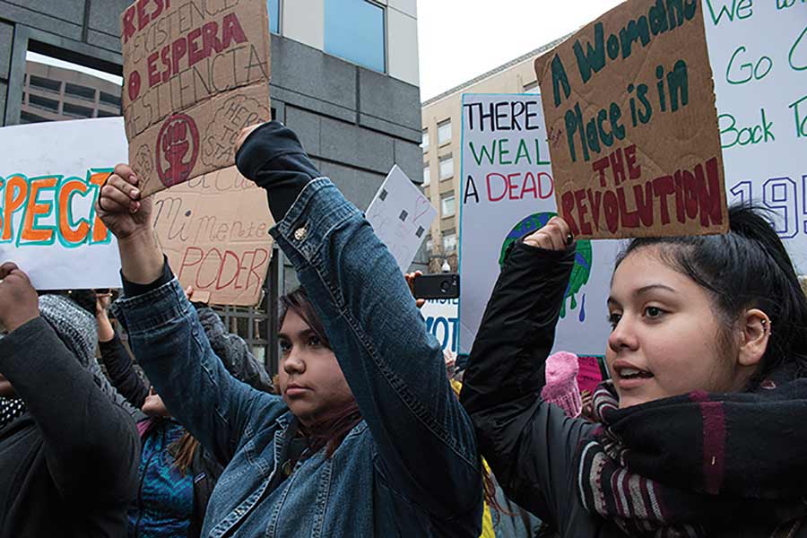 Three Knox students march in Washington D.C. holding signs. 