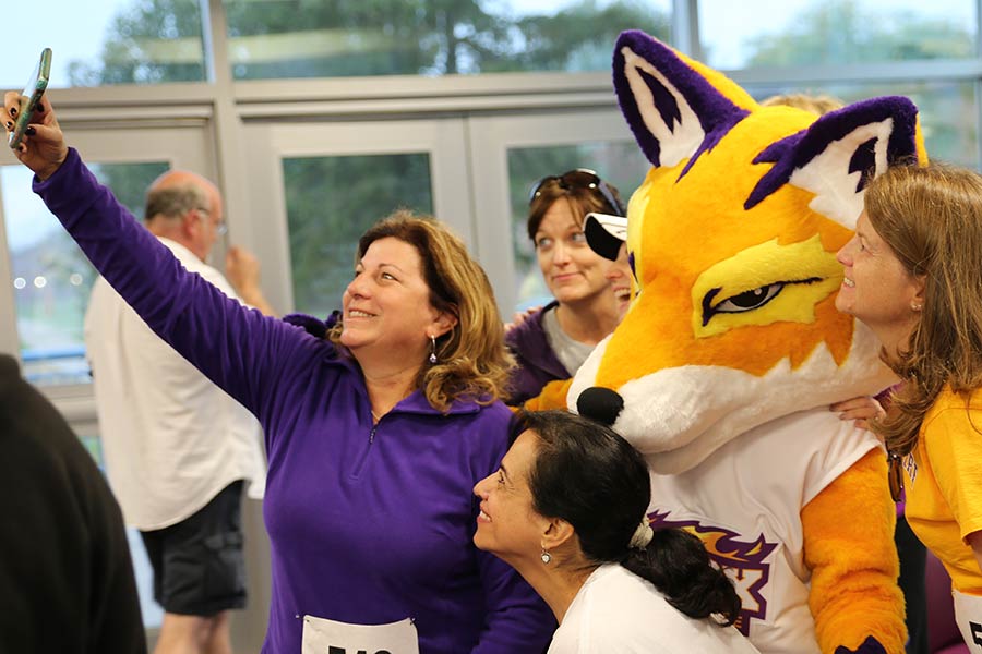 Alumni take a photo in the purple and gold with Knox's mascot, Blaze.