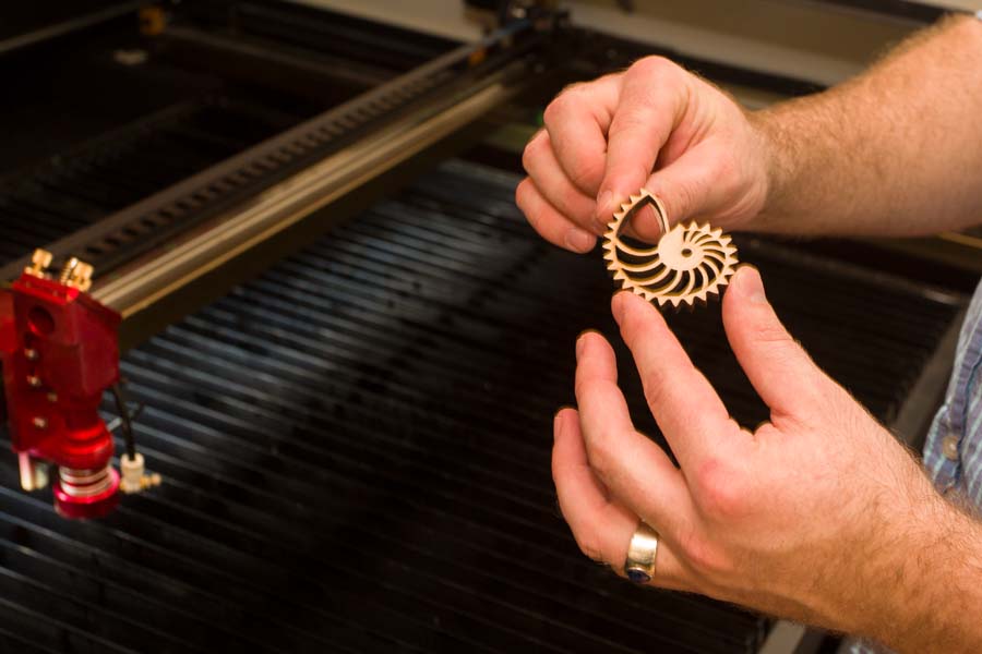 Biology Professor Nichlas Gidmark with piece created on laser cutter.