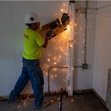 Sparks fly as a construction worker cuts into a wall on the Knox campus