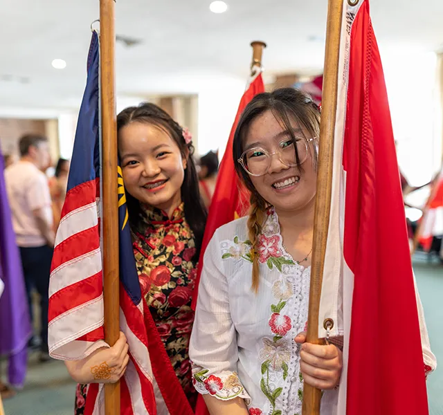 Two Knox international students smiling and holding the flags of the United States and Dhina