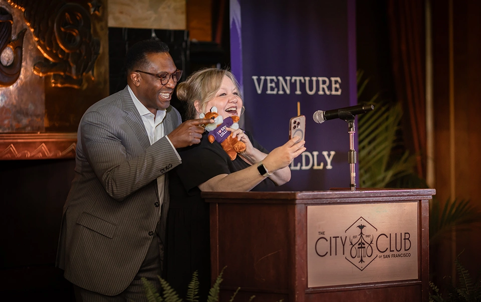 President C. Andrew McGadney and his Executive Assistant, Stacia Mattan, take a selfie at the podium with a stuffed Blaze. 